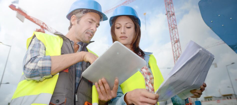 Two construction workers looking at papers together