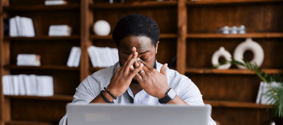 Man looking stressed sitting in front of laptop in office