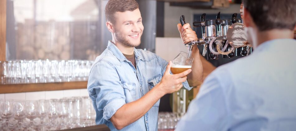 Man pouring a glass of beer behind bar