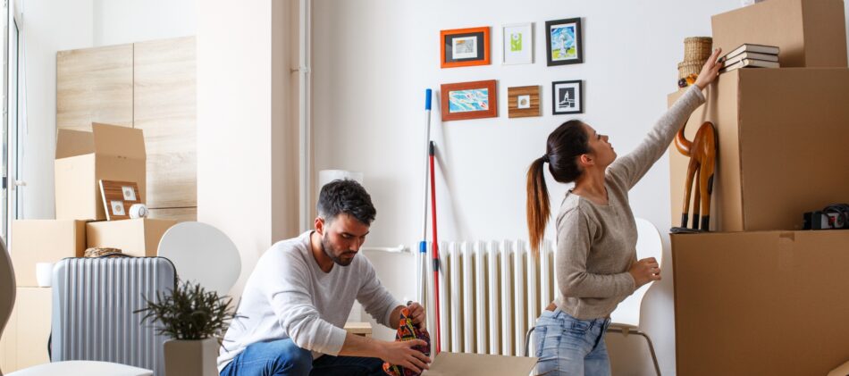 Young couple packing boxes in a mostly empty living room after a renoviction