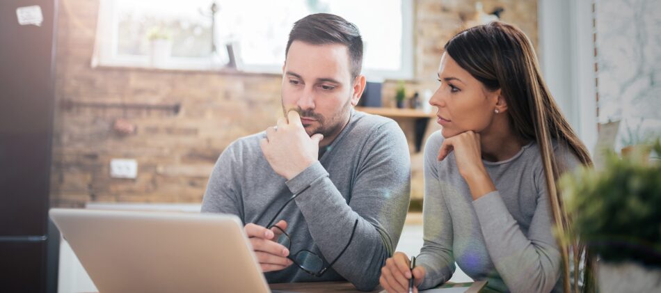Young couple looking perplexed at laptop