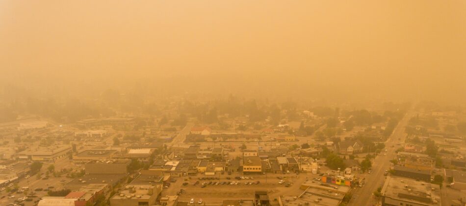 Aerial view of a town with heavy smoke giving it an orange hue