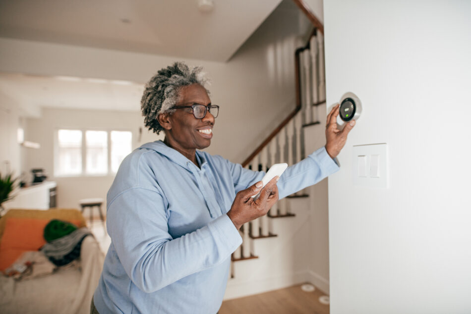 Senior looking at smart thermometer and smart home technology