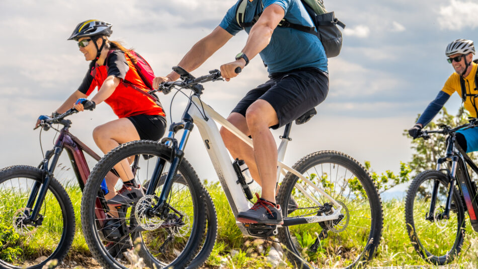 Mid adult men and women friends group riding electric mountain bikes together