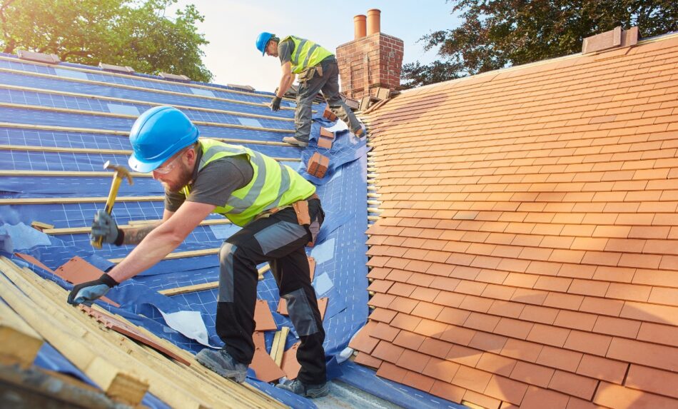 Workers putting new roof on house