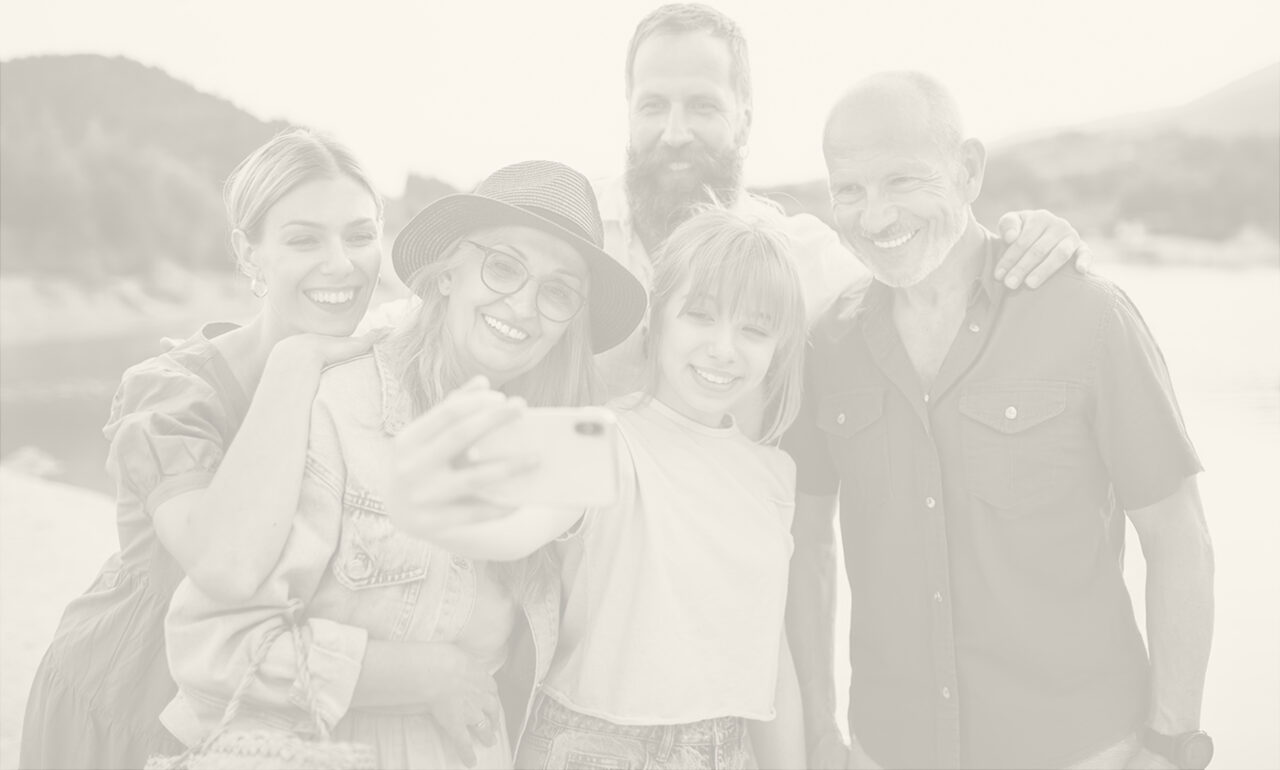 Multi-generational family photo of five smiling people on a beach